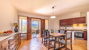 Una cucina moderna con mobili in legno, un tavolo da pranzo con sedie e vista attraverso la porta aperta.
