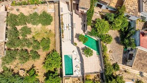 Una vista aerea di una zona residenziale con piscina, diversi edifici e vegetazione circostante.