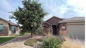 Una casa residenziale con facciata in mattoni, un garage e un prato curato.