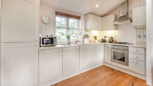Une cuisine moderne avec des meubles blancs, un four à micro-ondes encastré, une cuisinière et un évier.