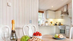 Une cuisine avec des meubles blancs, une hotte de cuisinière en acier inoxydable et une fenêtre équipée de stores.