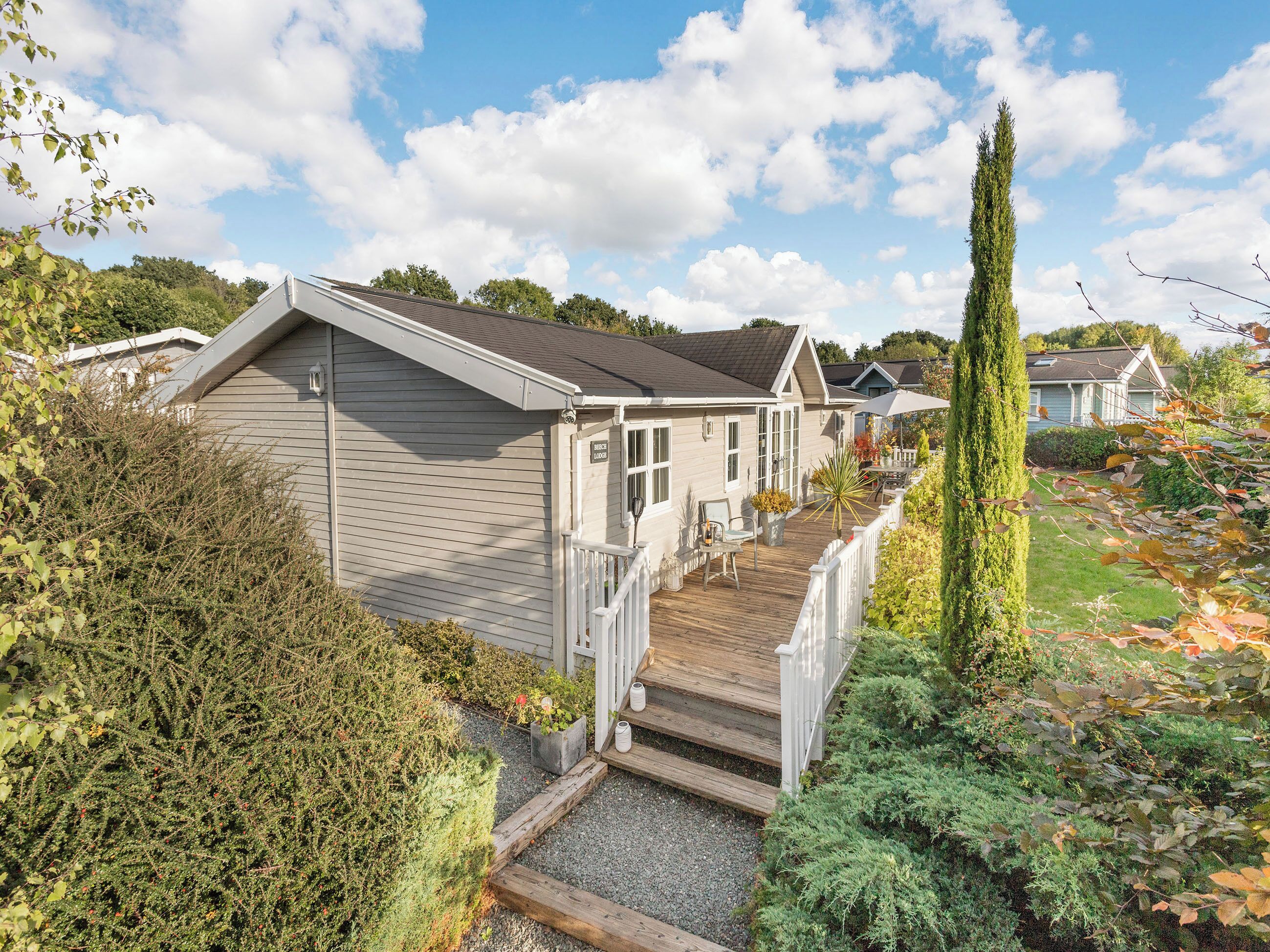 A residential property with a wooden deck, a covered patio, and a garden area.