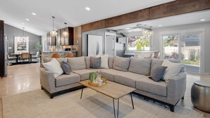 A modern living room with a sectional sofa, a coffee table, and a dining area with a table and chairs. - Private Pool, Hottub, Steamshower just 10 minutes from Grand Rapids (Grandville)