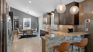 A modern kitchen with a central island, wooden cabinets, and pendant lighting. - Private Pool, Hottub, Steamshower just 10 minutes from Grand Rapids (Grandville)