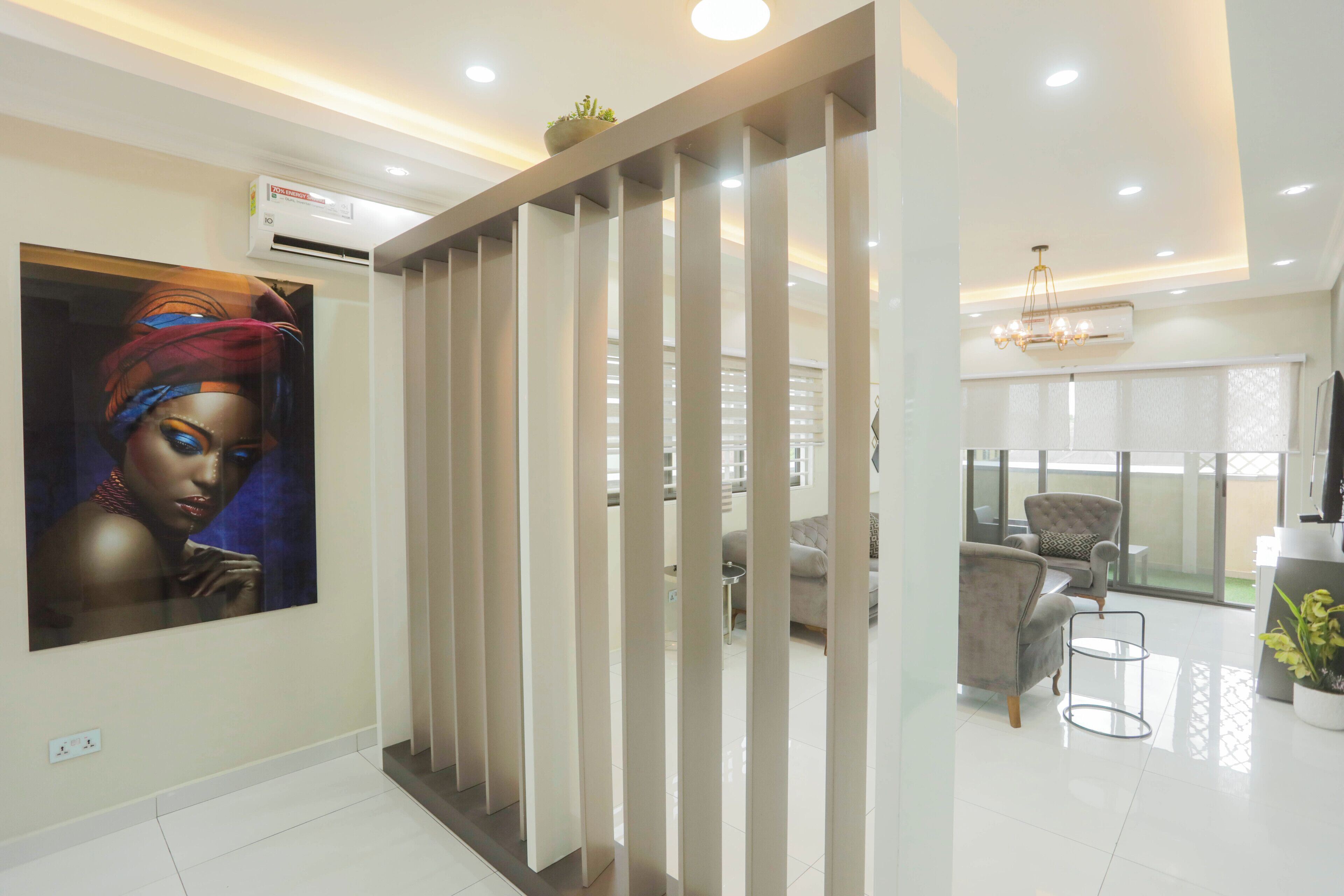 A modern hotel lobby with a large painting, a reception desk, and a seating area with a view of the outdoors.
