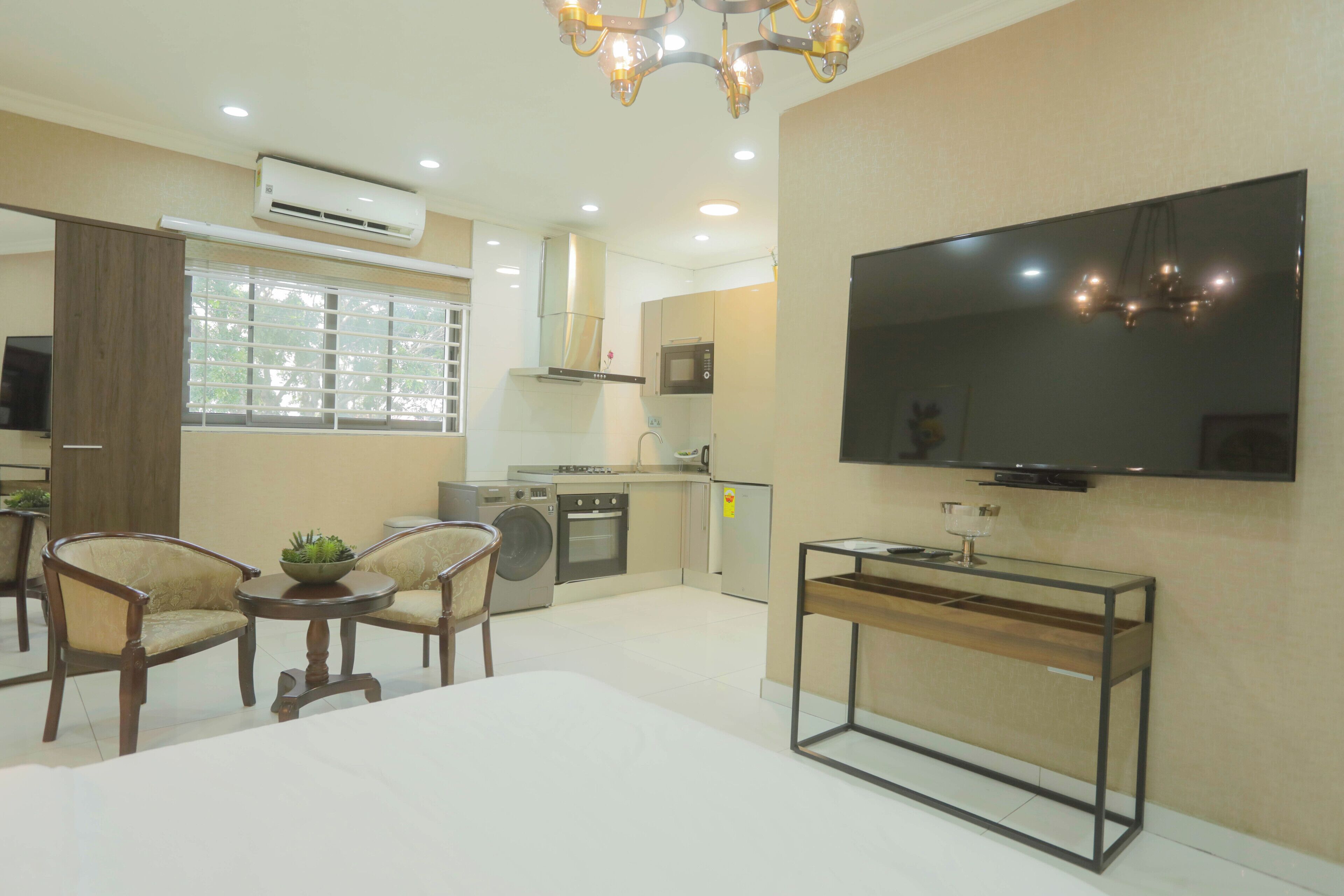 Una sala de estar moderna con televisor de pantalla plana, un comedor con sillas, una cocina equipada y un amplio ventanal.