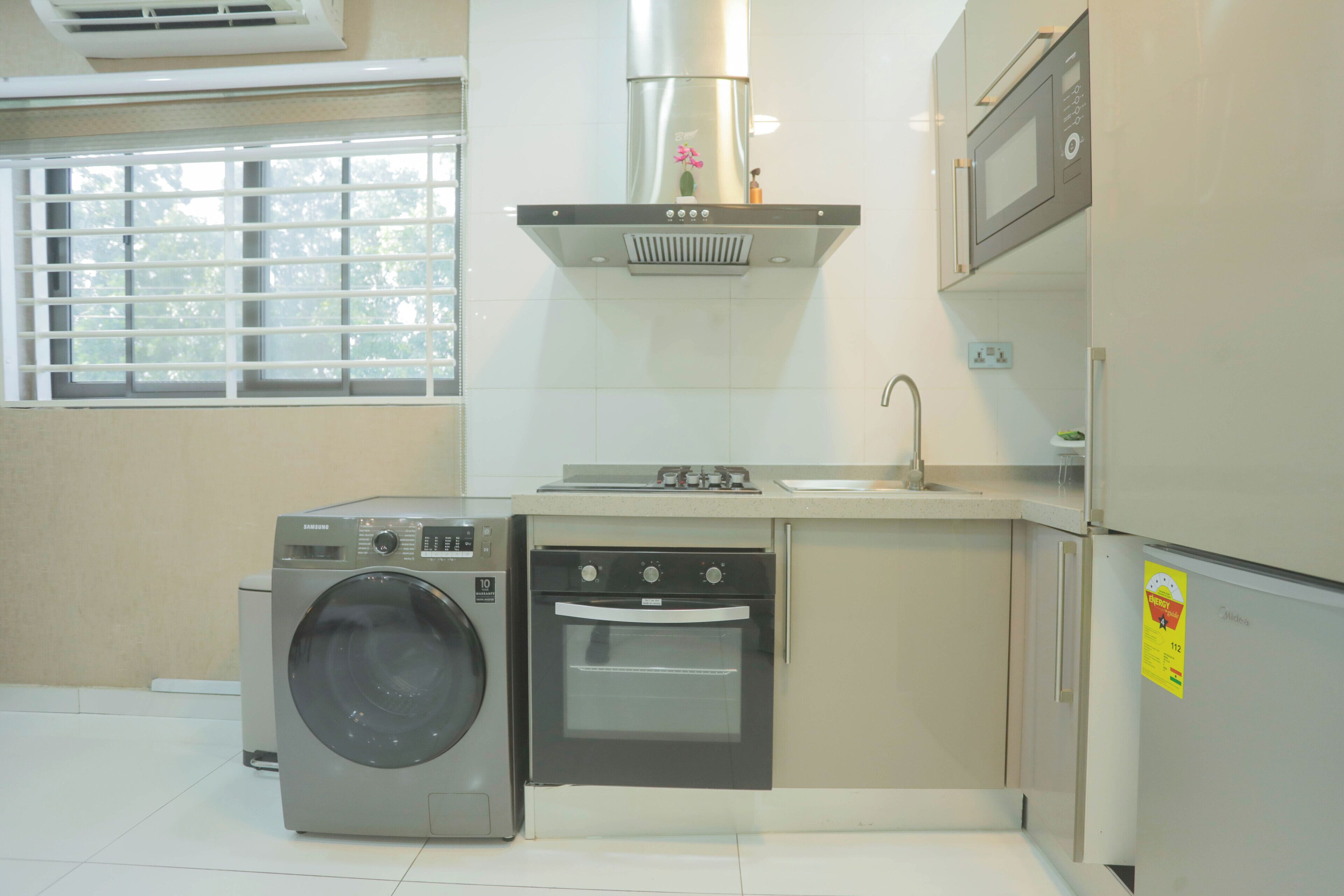 A compact kitchen with a washing machine, oven, and microwave.