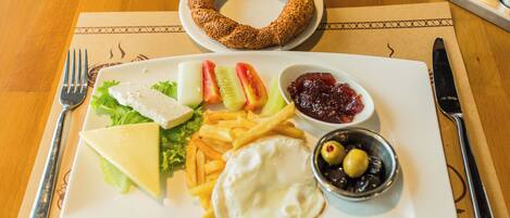 Une assiette contenant un sandwich, des frites, un œuf au plat et une salade.