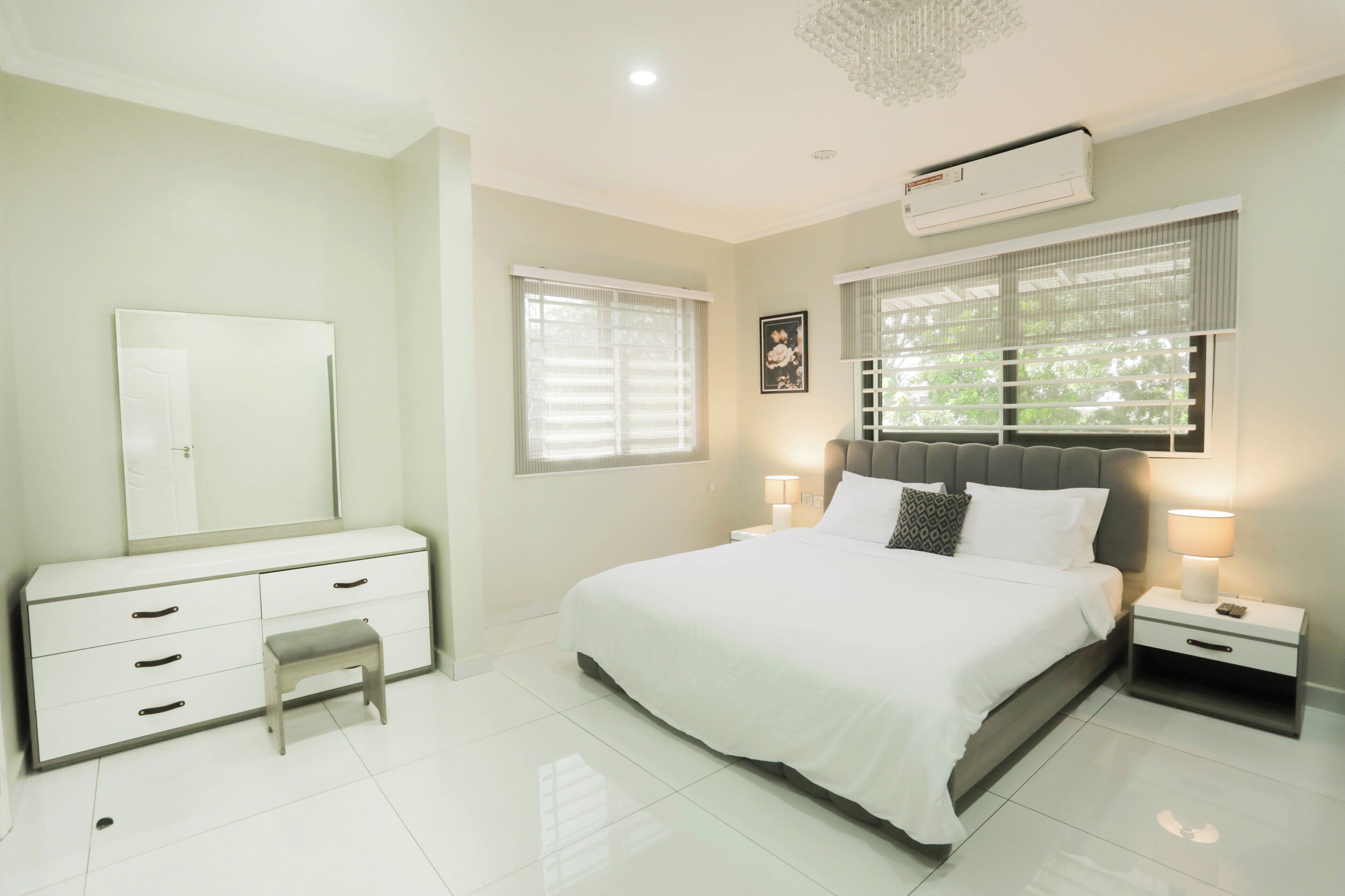 A bedroom with a bed, bedside tables, a dresser, and a mirror.