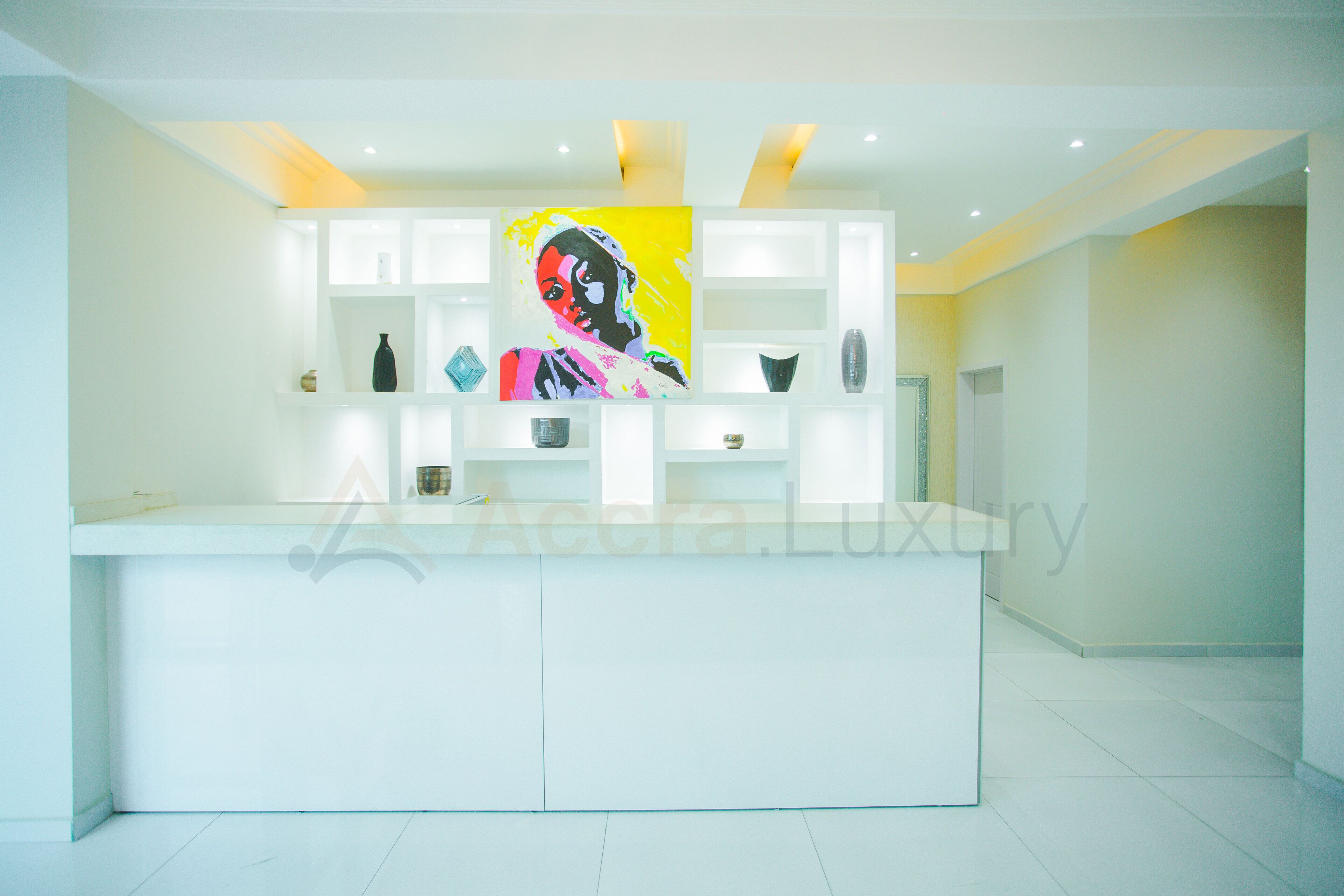 A reception desk with a colorful artwork above it, white walls, and a clean, modern design.