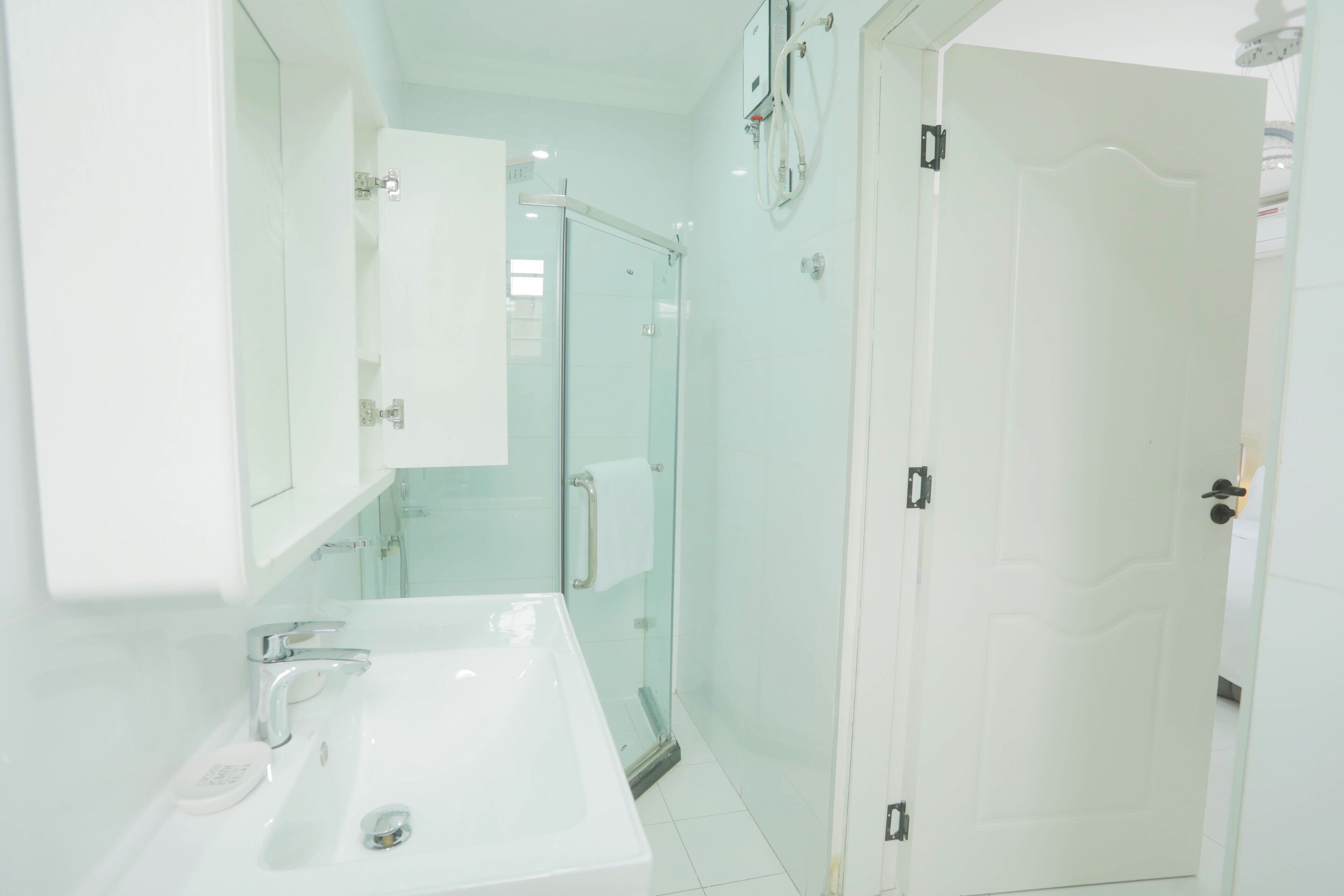 A modern bathroom with a white sink, mirror, and glass shower enclosure.