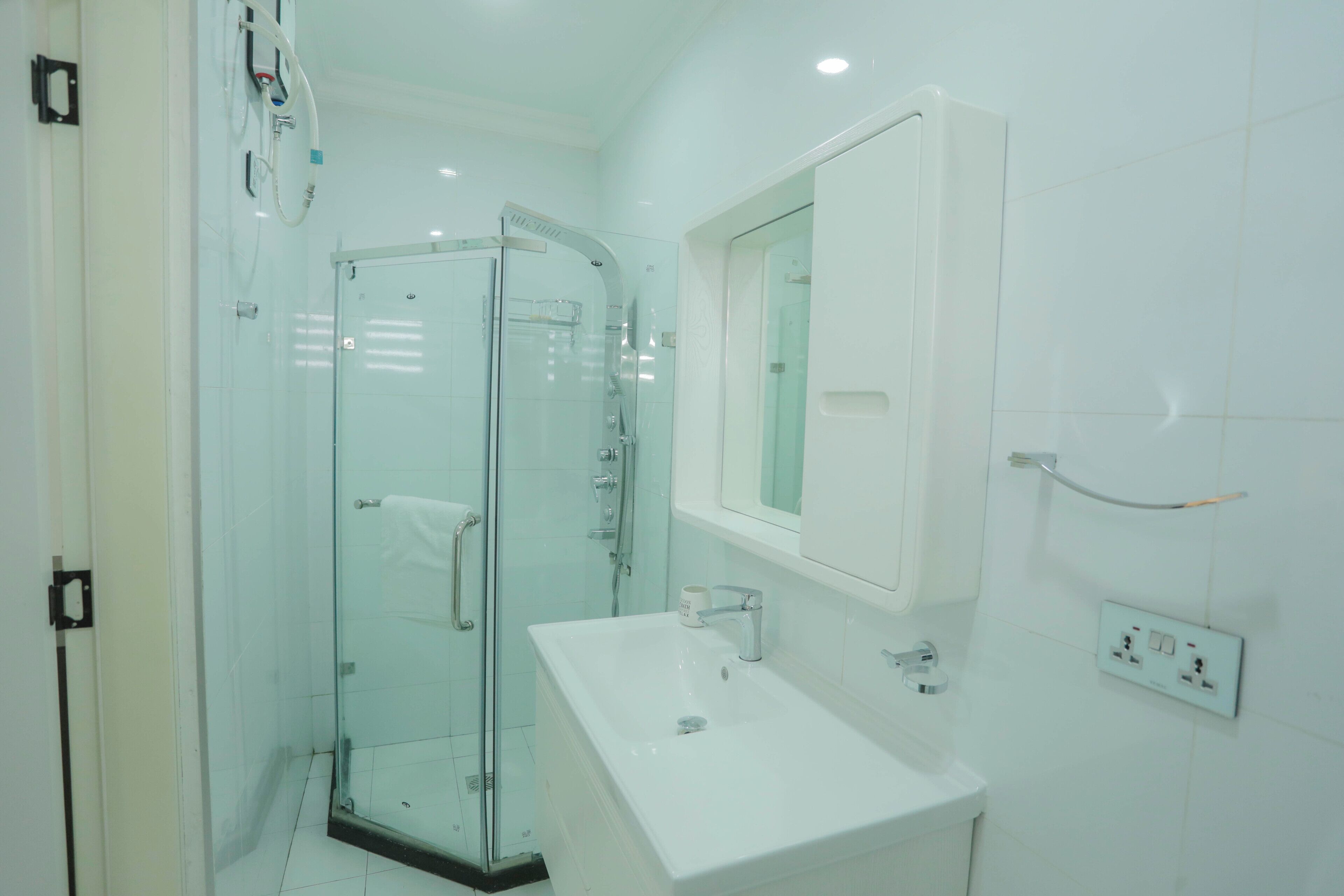 A modern bathroom with a glass shower enclosure, a white sink, and a mirror above the sink.