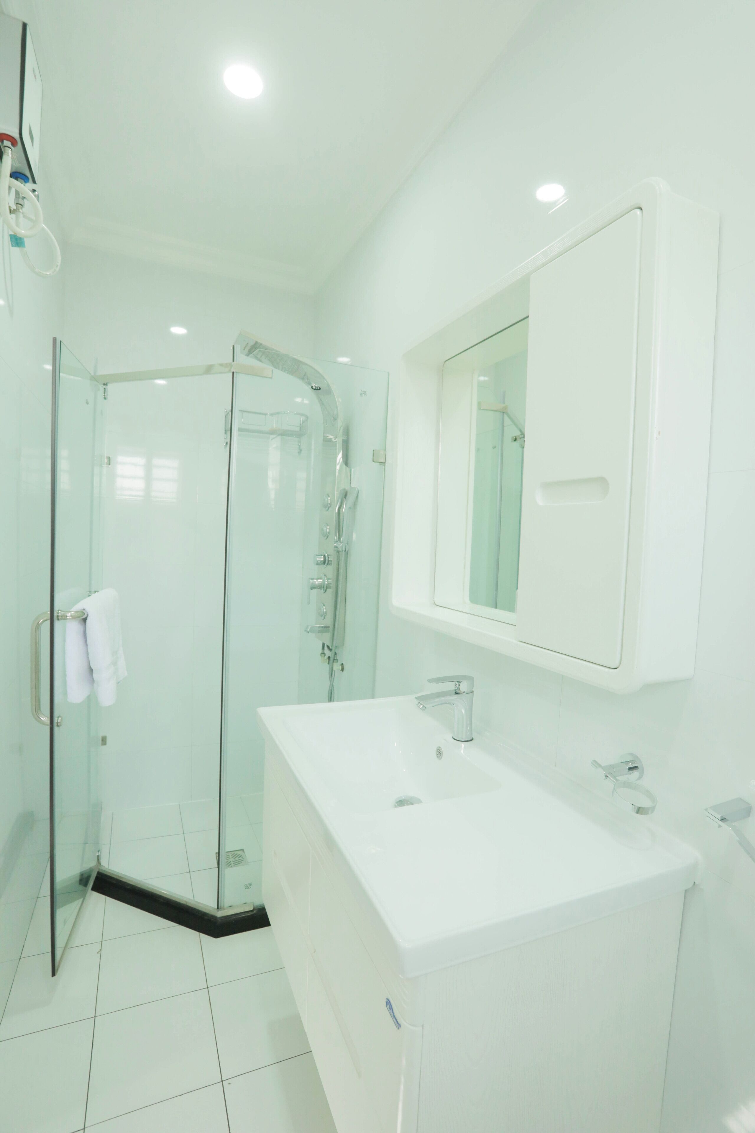 A modern bathroom with a glass-enclosed shower, a white sink, and a mirror above the sink.