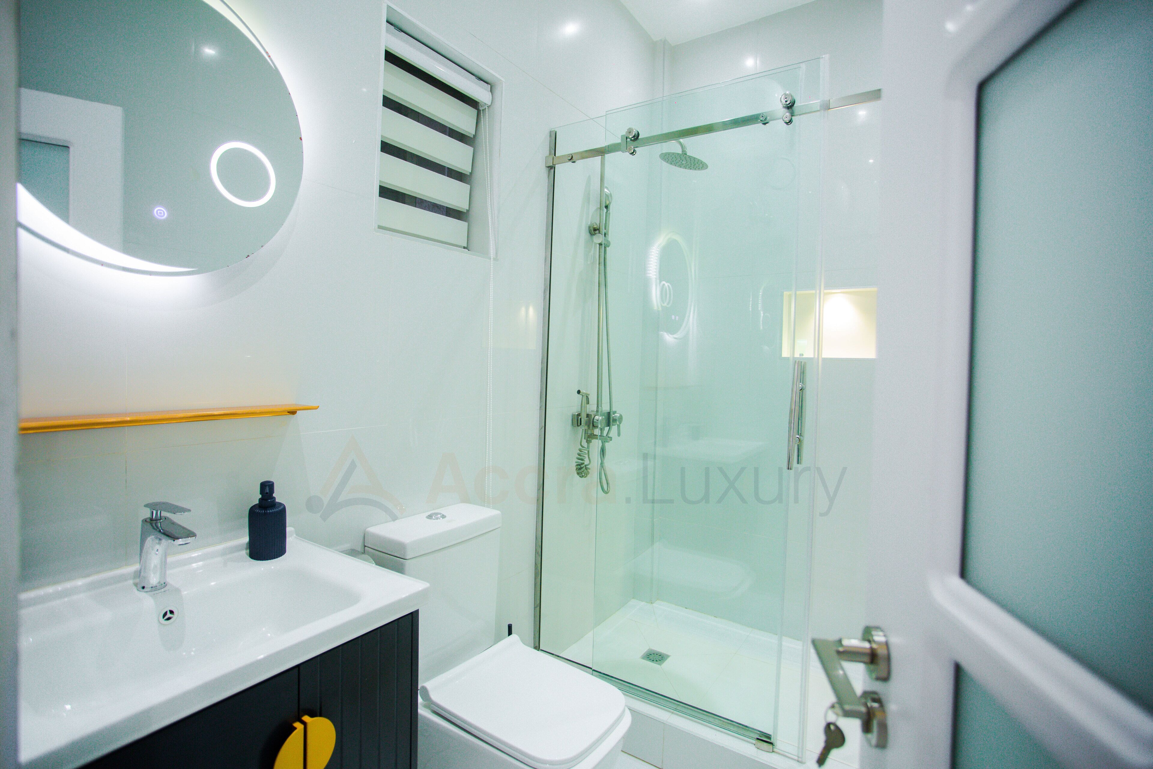 Un baño moderno con ducha de vidrio, lavamanos blanco y retrete.