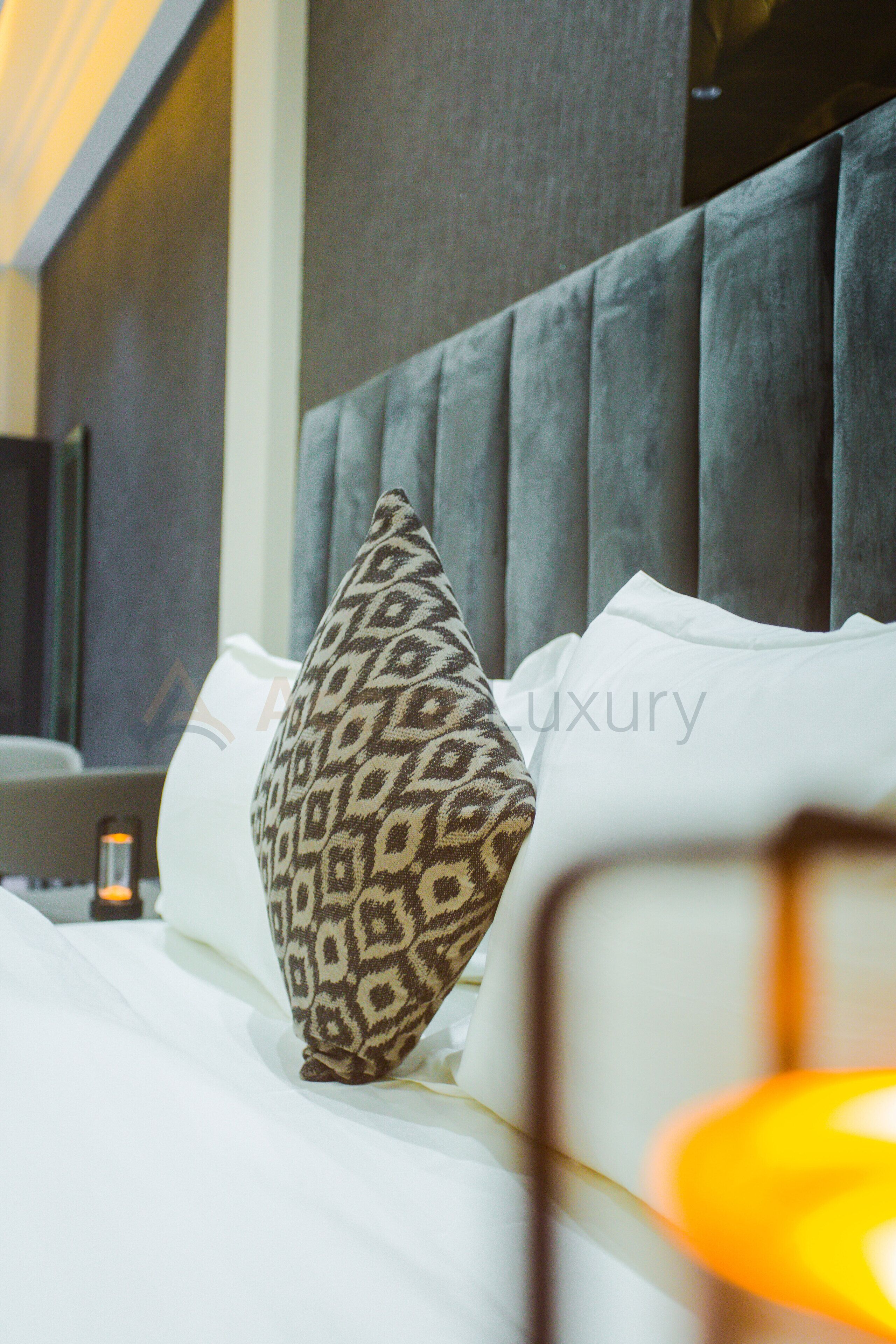 A bed with a patterned pillow and a headboard.