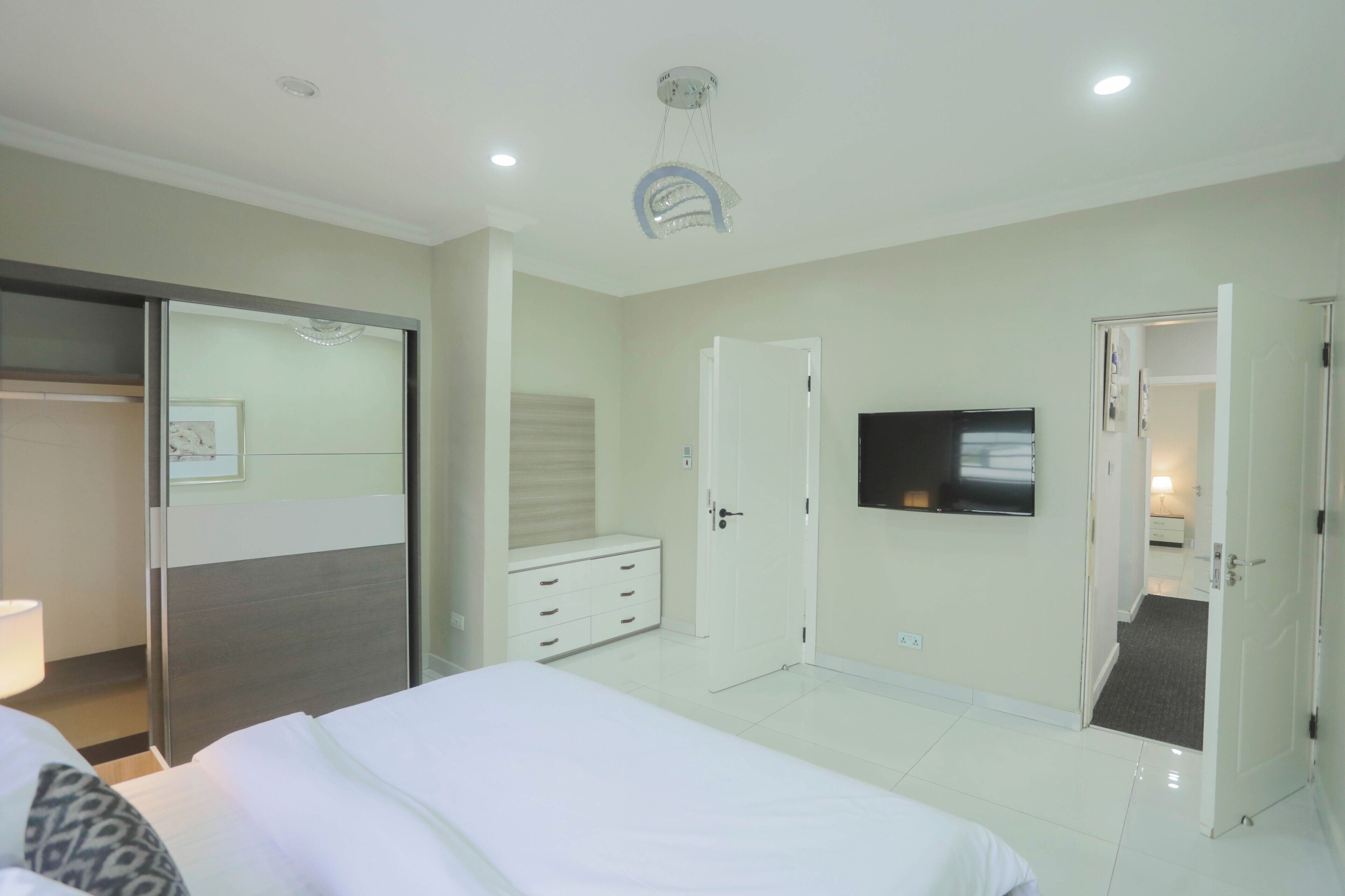 A hotel room with a bed, a dresser, a television, and a sliding door closet.