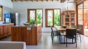 Una cocina amplia con armarios de madera, una isla central con lavamanos y un comedor con mesa y sillas.