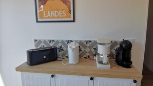 Et tekøkken med kaffemaskine, elkedel og brødrister på en træbordplade.
