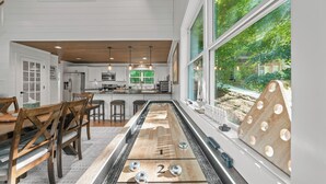 Cocina moderna con una larga mesa de comedor, sillas de madera y vistas al exterior.