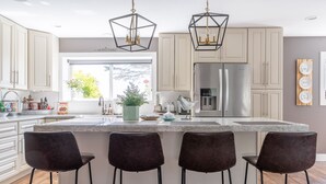 Una cocina moderna con una isla central, taburetes de bar e iluminación colgante.
