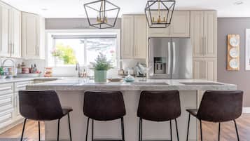 Une cuisine moderne dotée d’un îlot central, de tabourets de bar et de luminaires suspendus.