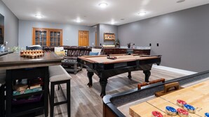 Un salón amplio con mesa de billar, mesa de futbolín y mesa de pool.