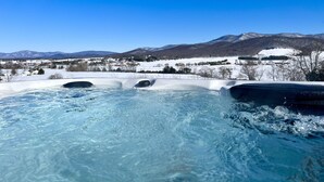 Un bain à remous avec un paysage enneigé et des montagnes en arrière-plan.