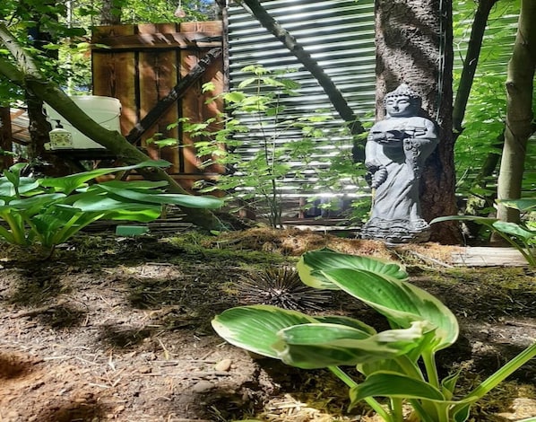 A garden with a statue, wooden fence, and various plants.