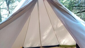 Una carpa con un colchón en su interior, un poste de metal y una pequeña mesa.