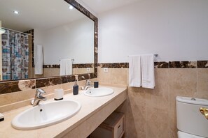Ein Badezimmer mit zwei Waschbecken, einem Spiegel und einer Toilette.
