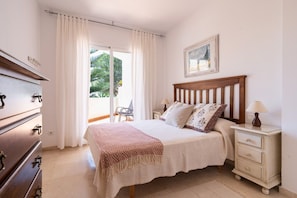 A bedroom with a bed, bedside tables, a dresser, and a window with curtains.