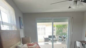 Ein Schlafzimmer mit einem Bett, Nachttischlampen, einem gewebten Korb und Blick ins Freie.