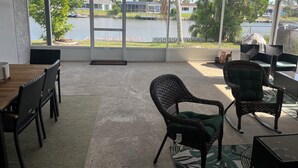 Eine überdachte Terrasse mit Seeblick, Gartenmöbeln und einem Betonboden.