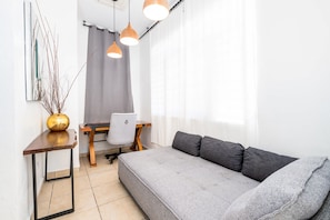 A modern living room with a grey sofa, a wooden table, a chair, and pendant lights.