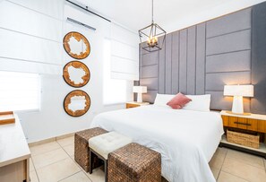 Un dormitorio moderno con una cama grande, mesitas de noche, un escritorio y espejos decorativos en la pared.
