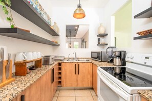 A modern kitchen with granite countertops, wooden cabinets, a built-in oven, and a microwave.