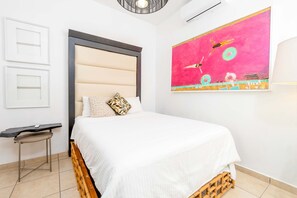 A bedroom with a bed, a small table, a wall-mounted air conditioner, and a large abstract painting. - 5 Bedroom Boho Beach House 30 steps from the beach (San Juan)