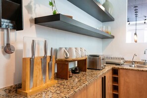 Una cocina con encimeras de granito, armarios de madera, un tostador integrado y una planta colgante.