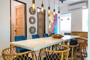 A dining area with a marble table, wicker chairs, and pendant lighting. - 5 Bedroom Boho Beach House 30 steps from the beach (San Juan)