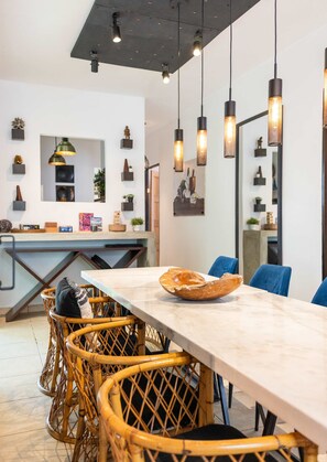 Un comedor moderno con una mesa de mármol, sillas de mimbre e iluminación colgante.