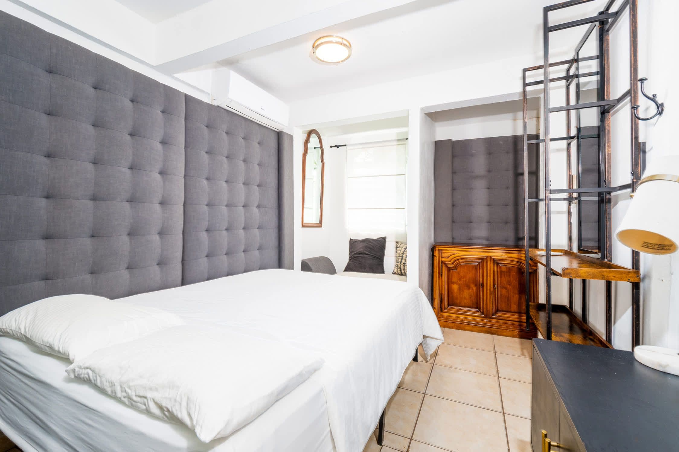 Ein Schlafzimmer mit einem großen Bett, einer Holzkommode und einem Spiegel mit Metallrahmen.