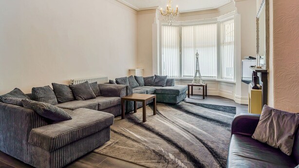 A living room with a sectional sofa, a coffee table, and a chandelier. - 7 bedroom accommodation in Blackpool (Blackpool)