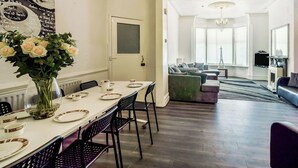 A dining area with a white table set for four, a vase of flowers, and a menu on the wall. - 7 bedroom accommodation in Blackpool (Blackpool)