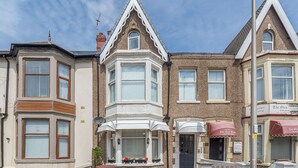 A row of terraced houses with bay windows, a front door, and a small garden area. - 7 bedroom accommodation in Blackpool (Blackpool)
