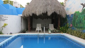 Una piscina con dos sillones de descanso y una estructura de techo de paja.