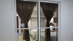 Una habitación con puerta corredera, dos camas y un espejo.
