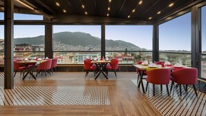 A restaurant with a terrace overlooking a cityscape and mountains. - Ramada Plaza BY Wyndham Ordu (Ordu)