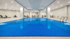 A large indoor swimming pool with multiple lounge chairs and a tiled floor. - Ramada Plaza BY Wyndham Ordu (Ordu)