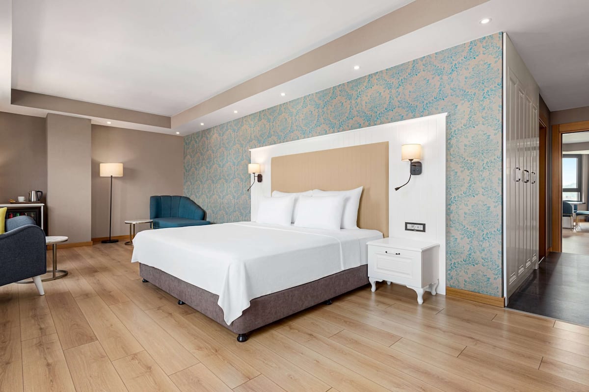 Ein modernes Hotelzimmer mit einem großen Bett, Nachttischen, einem Schreibtisch und einem Sessel.