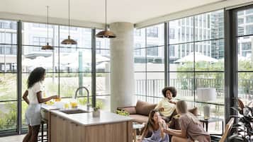 A modern kitchen with large windows, a central island, and a seating area with a sofa and chairs.